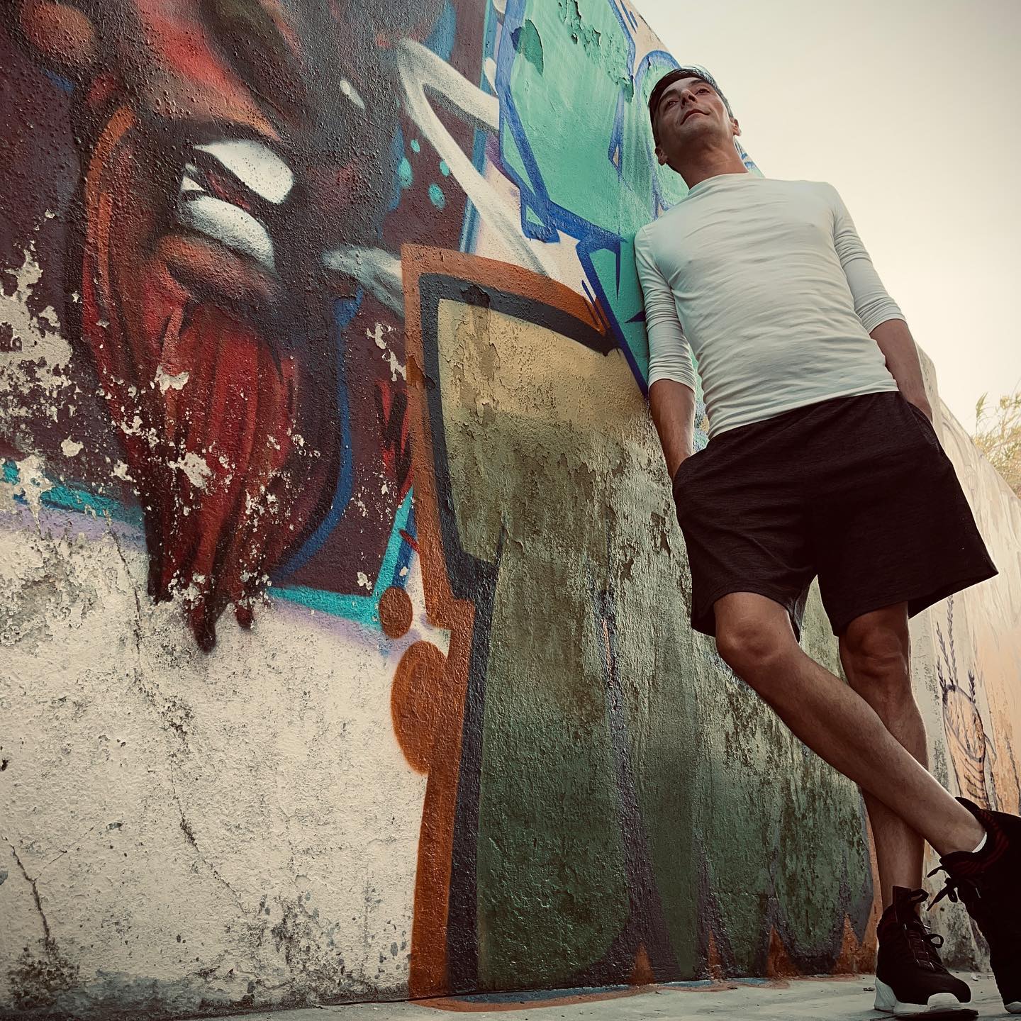 Cormik portrait by graffiti wall